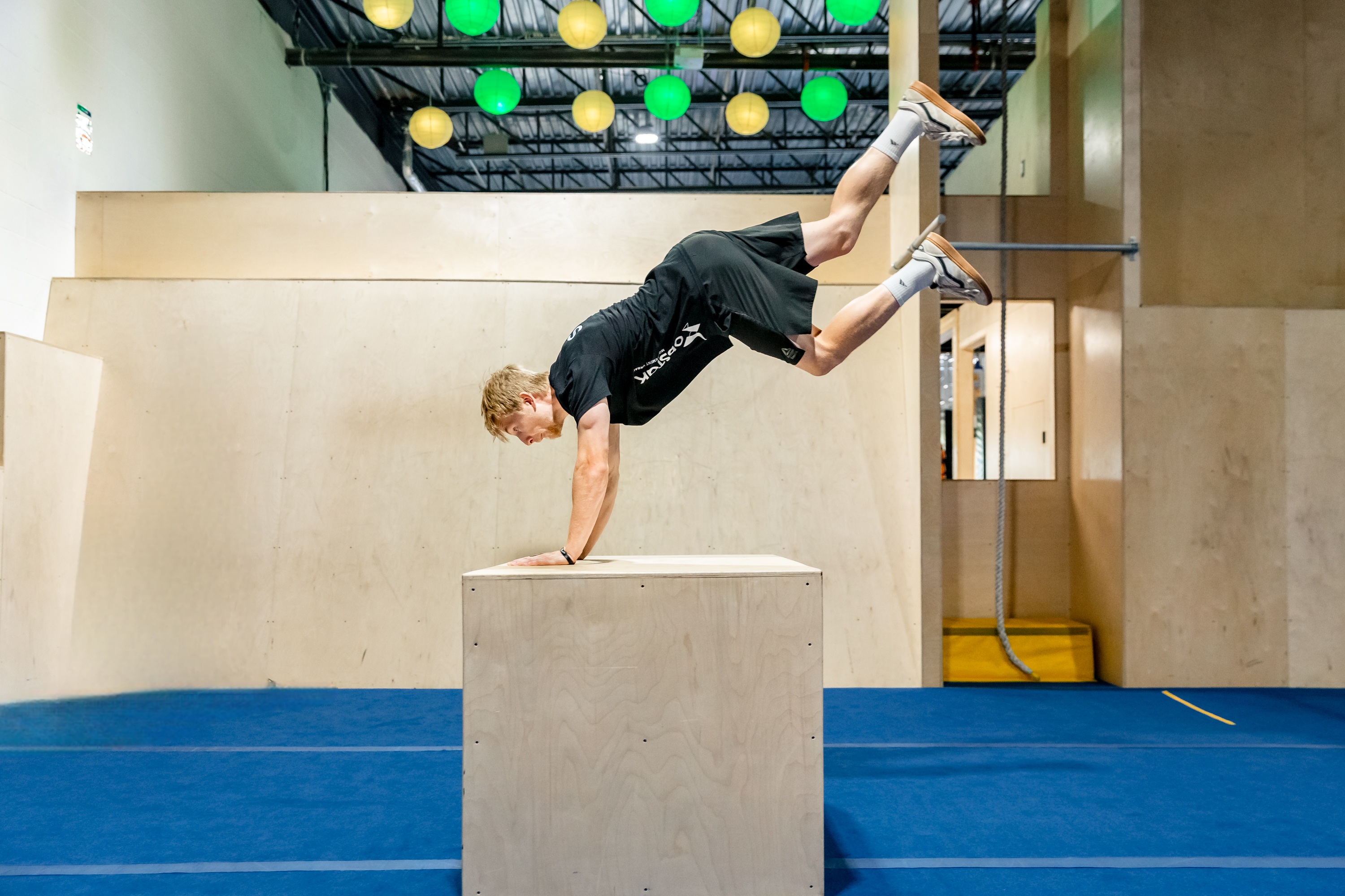 Un coach adulte r&eacute;alise un saut de chat en puissance, d&eacute;montrant contr&ocirc;le et fluidit&eacute;.